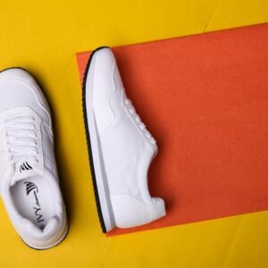 White sneakers displayed on a colorful orange and yellow background, highlighting modern fashion style.
