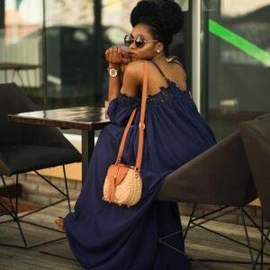 Stylish woman in sunglasses sitting outdoors at a café, exuding fashion and elegance.